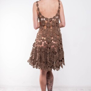 May include: A brown crochet dress with a loose fit and a scalloped hem. The dress is made of a delicate, open-weave fabric.