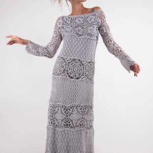 May include: A long, gray crochet dress with a loose fit and a flowing skirt. The dress features a variety of crochet patterns, including flowers, diamonds, and circles.
