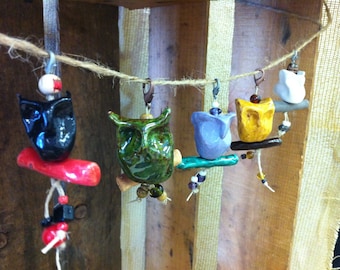May include: A string of colourful ceramic owl charms with beads and a red, green, blue, yellow and white colour scheme.