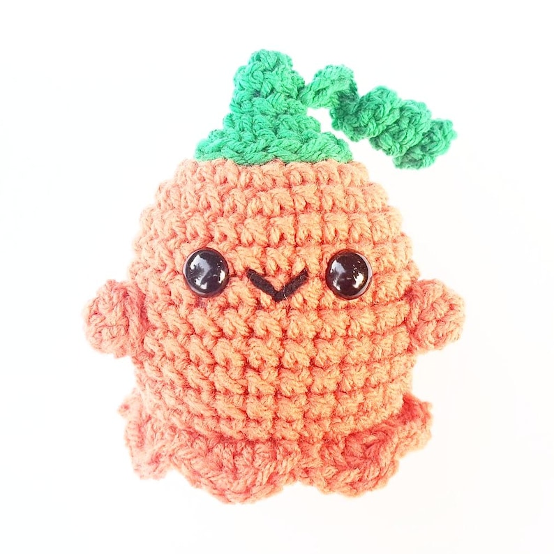 May include: A crocheted orange pumpkin-shaped plush toy with a green stem and black eyes.