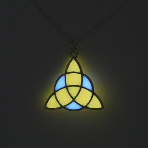 May include: A black chain necklace with a glow-in-the-dark pendant. The pendant is a yellow and blue Celtic knot design.