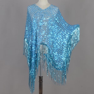 May include: A light blue sequin shawl with a V-neck design and fringe detailing. The shawl is displayed on a mannequin, showcasing its shimmering texture and draping. The fringe hangs from the bottom edges.
