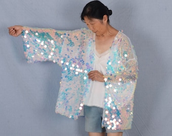 May include: A white iridescent sequined kimono with long sleeves. The kimono is sheer and has a loose fit.