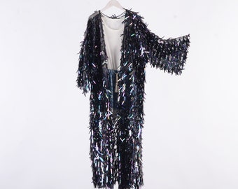 May include: A long black sequined cardigan with iridescent sequins. The cardigan has a V-neck and long sleeves.