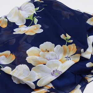 May include: A navy blue chiffon scarf with a floral print featuring white and yellow flowers.