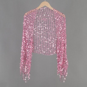 Peut inclure: Un châle rose pailleté avec des franges sur les manches. Le châle est fait d'un tissu en maille délicat et est orné de petites paillettes rondes.