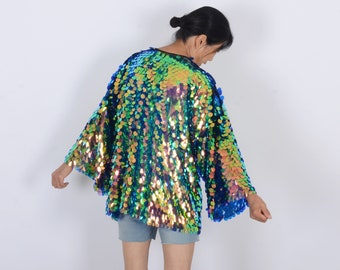May include: A shimmering, iridescent sequin jacket in shades of teal, green, and gold. The jacket has a loose, flowing design with wide sleeves. The sequins catch the light, creating a dazzling effect. The jacket is a statement piece.