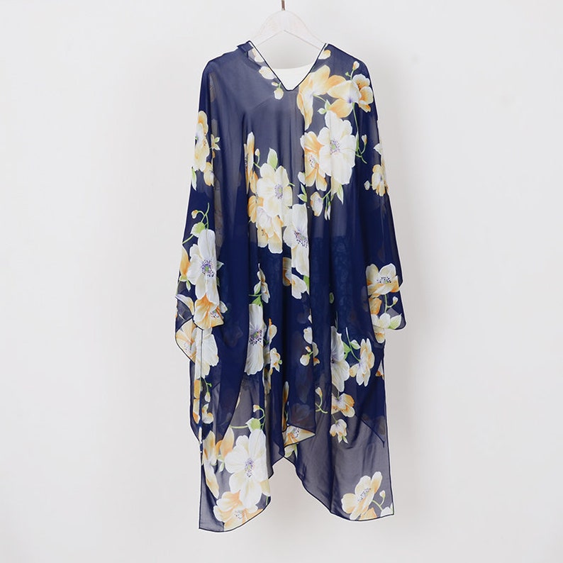 May include: A navy blue sheer floral print kimono with a V-neckline. The kimono has a white and yellow floral pattern.
