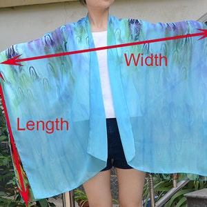 May include: A light blue sheer kimono with a colorful abstract print. The kimono is shown being worn by a person and the length and width of the garment are marked with red lines and text.