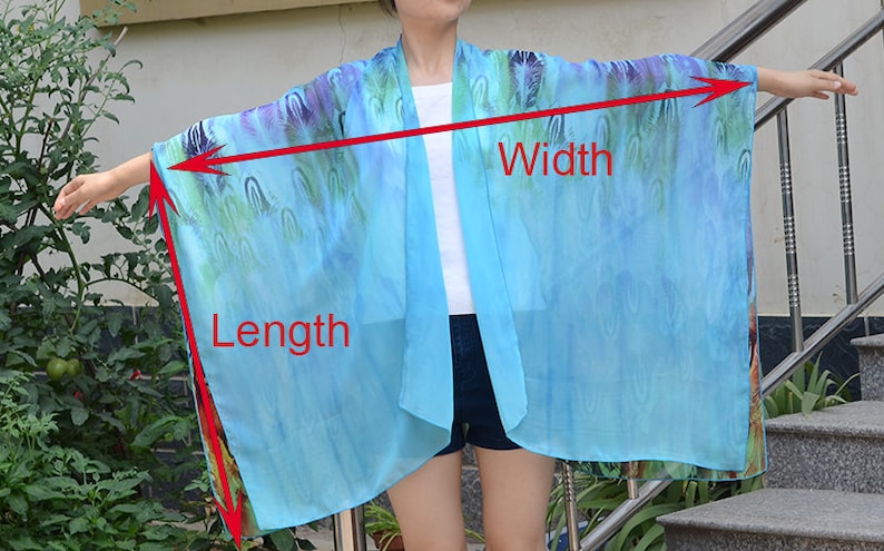 May include: A light blue sheer kimono with a colorful abstract print. The kimono is shown being worn by a person and the length and width of the garment are marked with red lines and text.