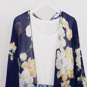 May include: A navy blue floral chiffon kimono with a white floral pattern. The kimono has long sleeves and a loose fit.