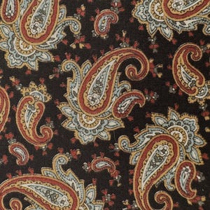 Puede incluir: Primer plano de una tela con un patrón de cachemira repetido. El diseño presenta grandes formas de lágrima ornamentadas en tonos de rojo, dorado y azul sobre un fondo marrón oscuro. La tela tiene una apariencia texturizada.
