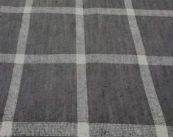 Può includere: Primo piano di un tessuto a quadri grigio e bianco. Il tessuto ha uno sfondo grigio scuro con un motivo a griglia di linee bianche. Le linee si intersecano per formare dei quadrati. Il tessuto sembra essere tessuto.