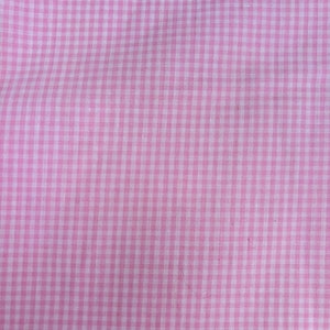 Könnte beinhalten: Nahaufnahme eines rosa-weiß karierten Stoffes. Das Muster besteht aus einem Raster aus kleinen, gleichmäßig verteilten Quadraten. Der Stoff hat ein weiches, leicht strukturiertes Aussehen mit dezentem Glanz. Die Farbe ist ein helles, pastellfarbenes Rosa.