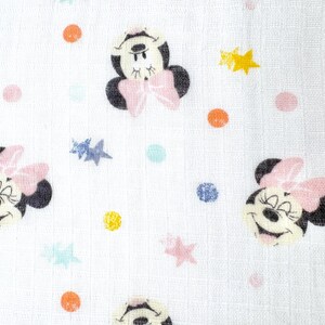 Op de afbeelding: Witte stof met een herhaald patroon van Minnie Mouse-gezichten, roze strikken en kleurrijke stippen en sterren. Het ontwerp heeft gele, oranje, roze, blauwe en groene accenten. De stof heeft een getextureerde uitstraling.
