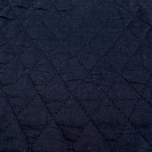 K&ouml;nnte beinhalten: Nahaufnahme eines marineblauen, gesteppten Stoffes. Der Stoff hat ein Rautenmuster, das durch gen&auml;hte Linien erzeugt wird. Die Textur wirkt weich und leicht zerknittert, mit subtilen Farbvariationen.