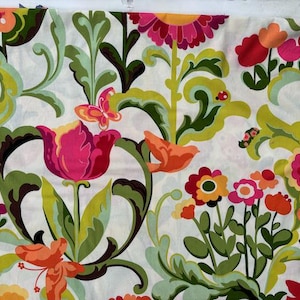 Op de afbeelding: Bloemenstof met een witte achtergrond, met grote roze, rode en oranje bloemen, groene bladeren en decoratieve krullen. Bevat een vlinder en vogels. De stof is 100% katoen.