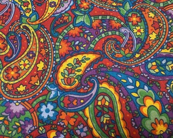 Könnte beinhalten: Ein lebendiges, farbenfrohes Paisley-Muster mit einem sich wiederholenden Design aus tropfenförmigen Motiven mit aufwendigen floralen und wirbelnden Details. Der Stoff zeigt eine reichhaltige Palette an Rot-, Orange-, Gelb-, Grün-, Blau- und Lilatönen.