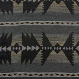 Könnte beinhalten: Ein gewebter Stoff mit einem sich wiederholenden geometrischen Muster in Schwarz, Anthrazitgrau und gedämpftem Beige. Das Design umfasst große dreieckige Formen, horizontale Bänder aus kleinen Dreiecken und Rautenmotive in einer strukturierten Anordnung.