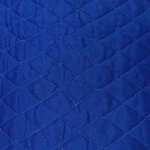 K&ouml;nnte beinhalten: Nahaufnahme eines leuchtend blauen, gesteppten Stoffes. Der Stoff weist ein Rautenmuster auf, das durch gen&auml;hte Linien erzeugt wird. Die Textur wirkt weich und leicht zerknittert, mit subtilen Variationen im Blauton.