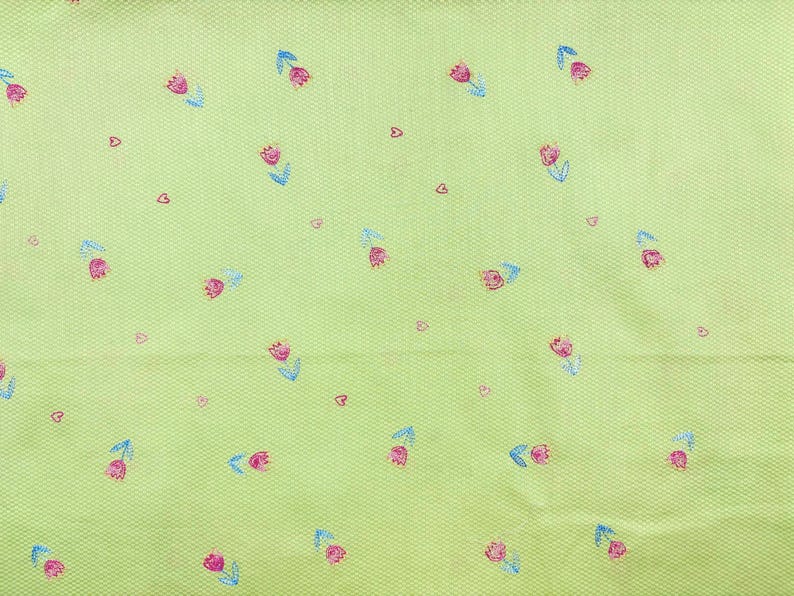 May include: A light lime green fabric featuring a repeating pattern of small pink tulips with blue stems and leaves, interspersed with tiny dark pink heart shapes. The material has a fine, textured, woven grid pattern across the entire surface.