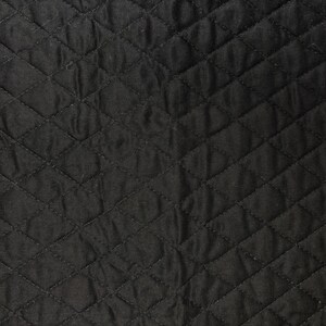 K&ouml;nnte beinhalten: Nahaufnahme eines schwarzen, gesteppten Stoffes mit einem Rautenmuster. Der Stoff hat eine leicht zerknitterte Textur, und die N&auml;hte erzeugen ein gitterartiges Design. Die dunkle Farbe und Textur deuten auf ein strapazierf&auml;higes Material hin.