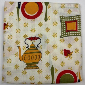 May include: A folded, off-white kitchen towel with a repeating pattern of yellow flowers, red plates, green utensils, and a yellow teapot. The towel has a vintage, retro aesthetic.