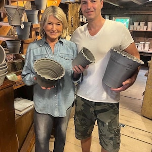 May include: Three gray ceramic pots with scalloped rims. The pots have a smooth, matte finish and a tapered cylindrical shape. The gray ceramic material is consistent across all three vessels, which vary in size from small to large.