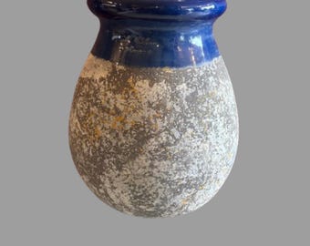 May include: A bulbous ceramic vase featuring a smooth, glossy deep blue glazed rim and neck. The main body of the vase has a textured, mottled finish in shades of gray, white, and subtle hints of ochre, creating a weathered, stone-like appearance.