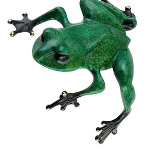 May include: A detailed sculpture of a frog in a vibrant green hue with a textured surface. The frog's feet and toes are black with gold accents. The frog is posed as if it is jumping or climbing.