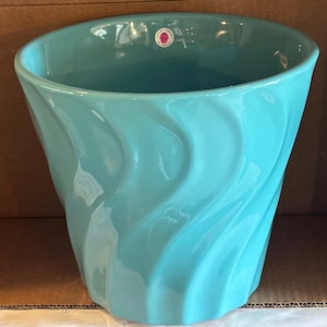 May include: A glossy turquoise ceramic planter with a vertical wavy, rippled texture on the exterior. The interior features a small circular sticker near the rim that reads Pottery Company Los Angeles in white text on a red background.