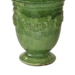 May include: A green ceramic vase with a pedestal base and a wide rim. The vase has a glossy finish and decorative relief patterns around the body. The text "VASE ANDUZE VERT" is at the bottom.