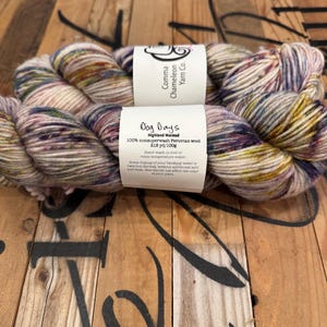May include: A skein of Dog Day's Highland Worsted yarn in a multi-colored pattern. The yarn is 100% nonsuperwash Peruvian wool and is 218 yards per 100 grams. The yarn is hand-dyed and has a variegated color pattern.
