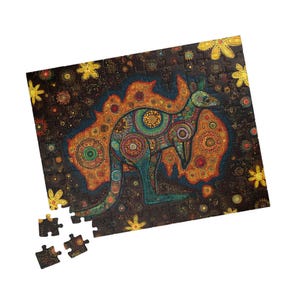 Pode incluir: Um quebra-cabeça colorido com um design artístico de canguru. O canguru é verde-azulado e adornado com padrões intrincados. O fundo é escuro com motivos florais e de pontos. Várias peças do quebra-cabeça estão separadas.
