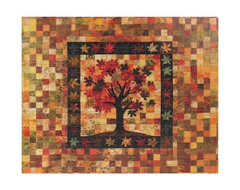 May include: A handmade quilt featuring a central image of a tree with red and orange leaves, set against a warm, autumnal background. The quilt is framed by a border of small, colorful squares, creating a patchwork effect. The tree's silhouette is dark, contrasting with the vibrant foliage.