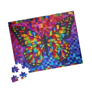 May include: A colourful jigsaw puzzle depicting a butterfly. The butterfly's wings are made up of small, multi-coloured squares in shades of red, orange, yellow, green, blue, and purple. A few puzzle pieces are separate.