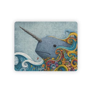 May include: A jigsaw puzzle featuring a blue narwhal with a long, spiraled horn. The narwhal is surrounded by swirling blue waves, colorful rainbow-like ribbons, and a dense cluster of small, vibrant flowers against a light blue background.