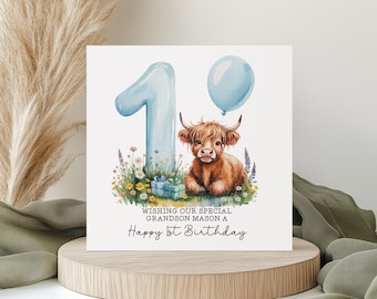 May include: A birthday card featuring a watercolor illustration. A light blue number 1 balloon and a blue balloon float above a Highland cow. Text reads, "Wishing our special grandson Mason a Happy 1st Birthday."