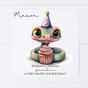 May include: A birthday card featuring a cartoon snake wearing a party hat and holding a cupcake with a lit candle. The card says "Wishing a special grandson a very happy 5th birthday".