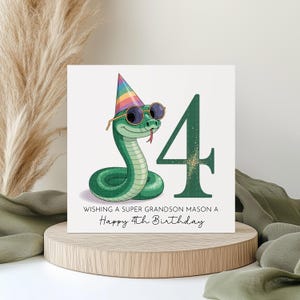 May include: A birthday card with a cartoon green snake wearing sunglasses and a party hat. A large number 4 is next to the snake. The card reads, "Wishing a Super Grandson Mason a Happy 4th Birthday."