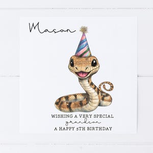 May include: A birthday card featuring a cartoon snake wearing a party hat. The card says "Wishing a very special grandson a happy 5th birthday".