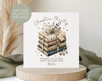Puede incluir: Tarjeta de cumpleaños cuadrada con una ilustración de libros apilados, adornados con flores y una cinta. El texto "Chapter Thirty" y "Wishing you a very happy 30th birthday Beth" están presentes. Una etiqueta indica "30".