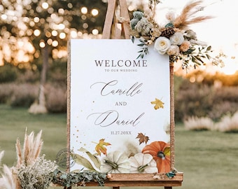 Könnte beinhalten: Ein weißes Willkommensschild mit rustikalem Jutesack-Hintergrund und Herbstdekoration. Das Schild lautet "Willkommen zu unserer Hochzeit, Camille und Daniel, 11.27.20XX".