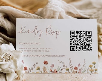 May include: A white card with the text "Kindly RSVP" in brown cursive writing. The text "BY JANUARY 23RD" is below in black. The text "PLEASE SCAN THE QR CODE OR VISIT OUR WEDDING WEBSITE TO RSVP." is below in black. The text "MILLEANDMARCOWEDDING.COM" is below in black. A QR code is in the upper right corner. A floral border is at the bottom of the card.
