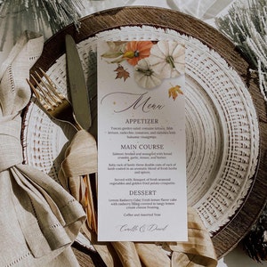 May include: A fall-themed wedding menu with a watercolor illustration of pumpkins and leaves. The menu includes appetizers, main course, dessert, coffee, and assorted teas. The names Camille and Daniel are at the bottom of the menu.