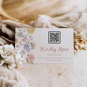 May include: A white RSVP card with floral illustrations in pink, yellow, and purple. The card includes a QR code and the text "Kindly Rsvp by April 12th, 20XX". The card is for a wedding.