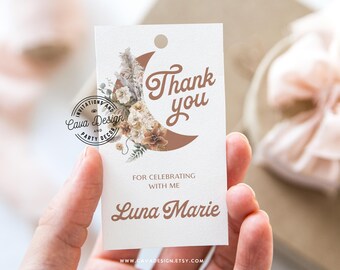 Op de afbeelding: Een wit bedankkaartje met een bruine halve maan en een bloemenontwerp. De tekst "Bedankt" is geschreven in een cursief schrift. De tekst "Voor het vieren met mij Luna Marie" staat onder de maan. Het websiteadres "www.cavadesign.etsy.com" is onderaan het kaartje gedrukt.