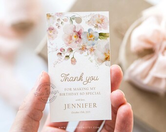 May include: A white thank you tag with a watercolor floral design in shades of pink and blue. The text reads "Thank you for making my birthday so special with love, Jennifer, October 15th, 2023, www.cava design.etsy.com".