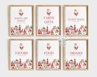 Pode incluir: Seis sinais imprimíveis com um tema de vila de inverno e ilustrações do Papai Noel. Os sinais dizem "Bebés são doces", "Cartões e presentes", "Livro de visitas", "Favores", "Comida" e "Bebidas".