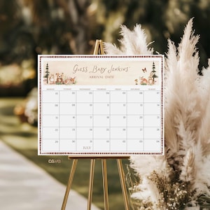 K&ouml;nnte beinhalten: Ein dekorativer Kalender auf einer goldenen Staffelei mit dem Text "GUESS BABY JENKINS ARRIVAL DATE" oben. Der Kalender hat ein Juli-Layout mit Daten und Illustrationen von Waldtieren. Der Hintergrund ist verschwommen mit neutralen T&ouml;nen.